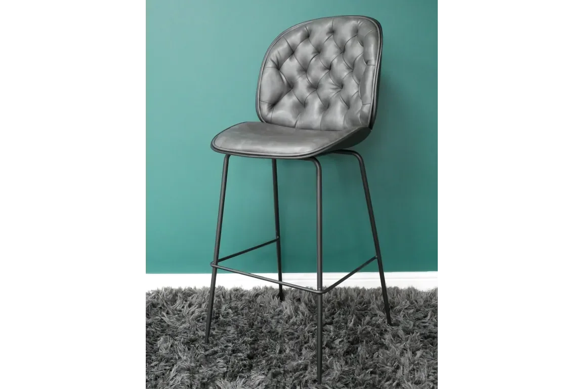 grey leather bar stool with tufted backrest and black metal legs on shaggy rug