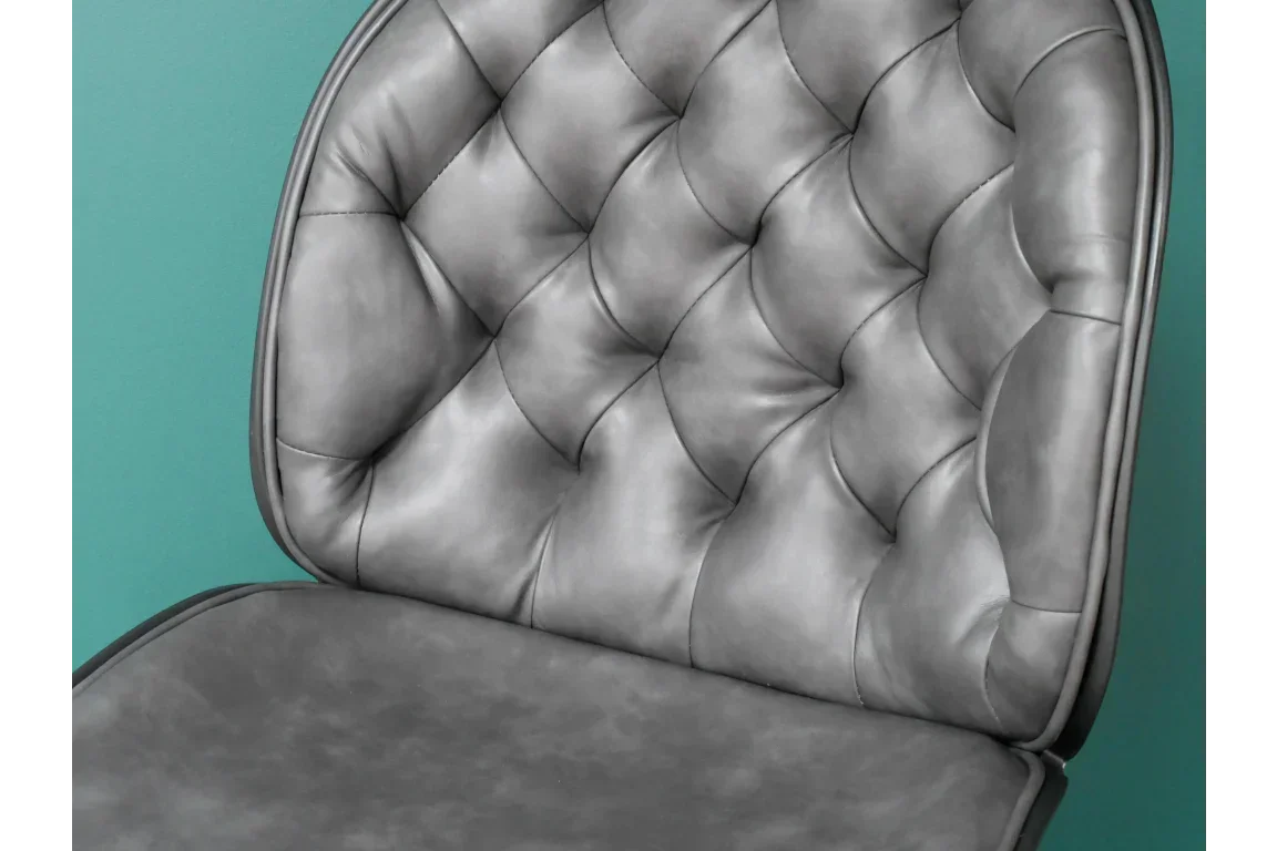 Grey leather dining chair with tufted backrest, close-up of upholstery and padding