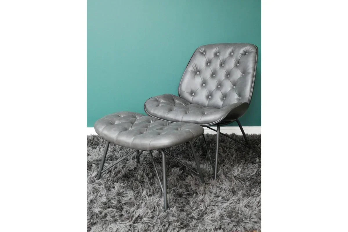 Grey leather armchair with matching footstool on shaggy rug against teal wall