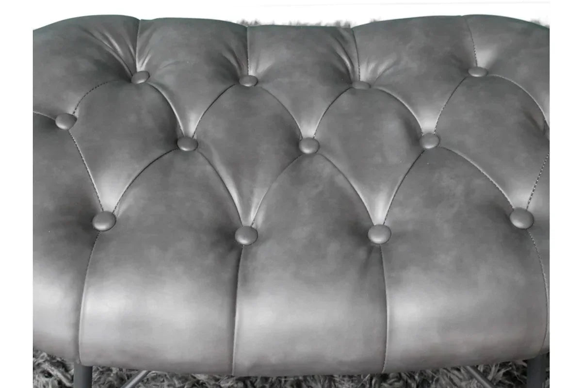 Close-up of grey faux leather bench seat with tufted upholstery and button detailing