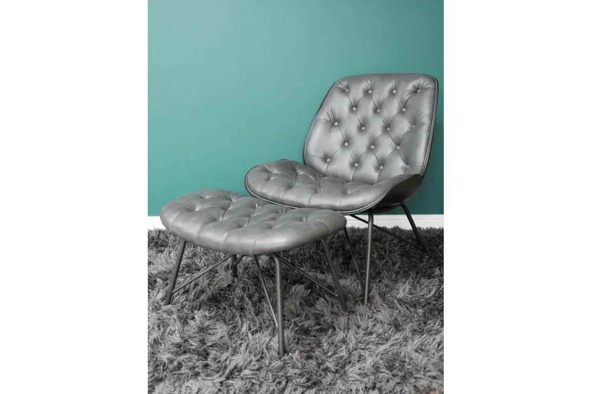 Grey leather accent chair with matching ottoman on shaggy rug