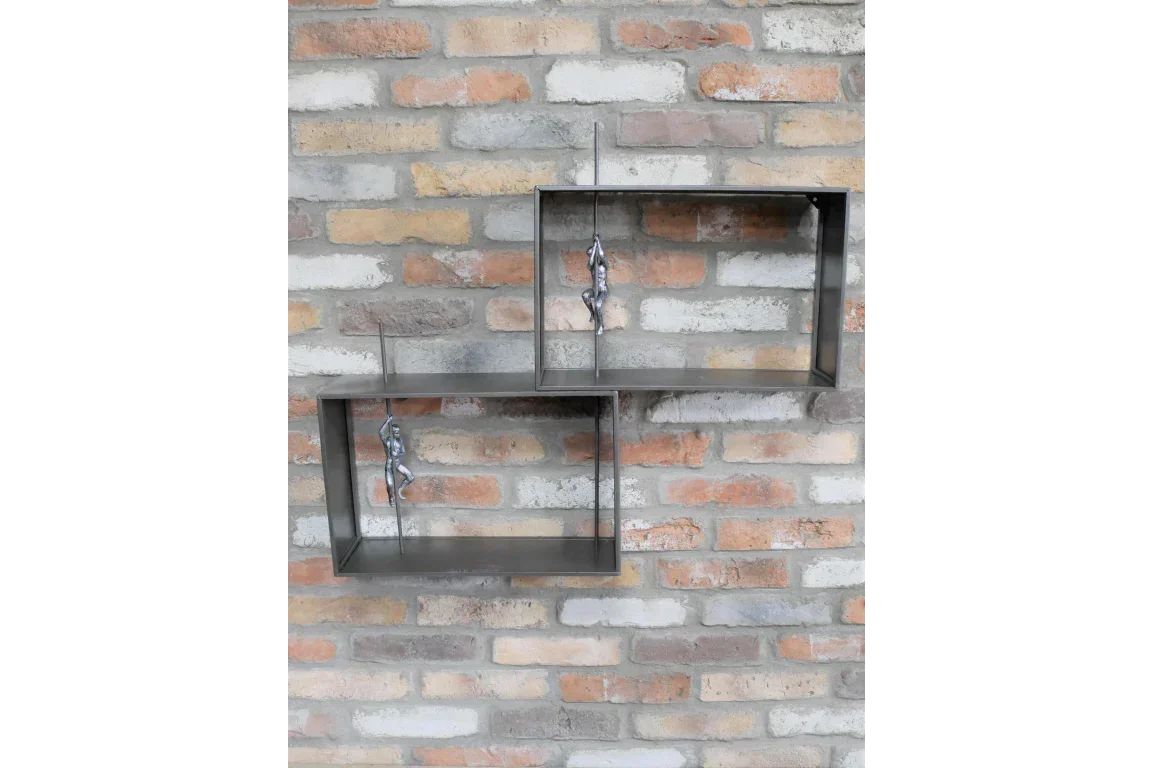 Metal wall shelf set with climbing figure ornaments on exposed brick wall