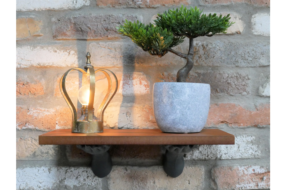 Floating brown wooden shelf supported by two black hand-shaped brackets, mounted on a brick wall.