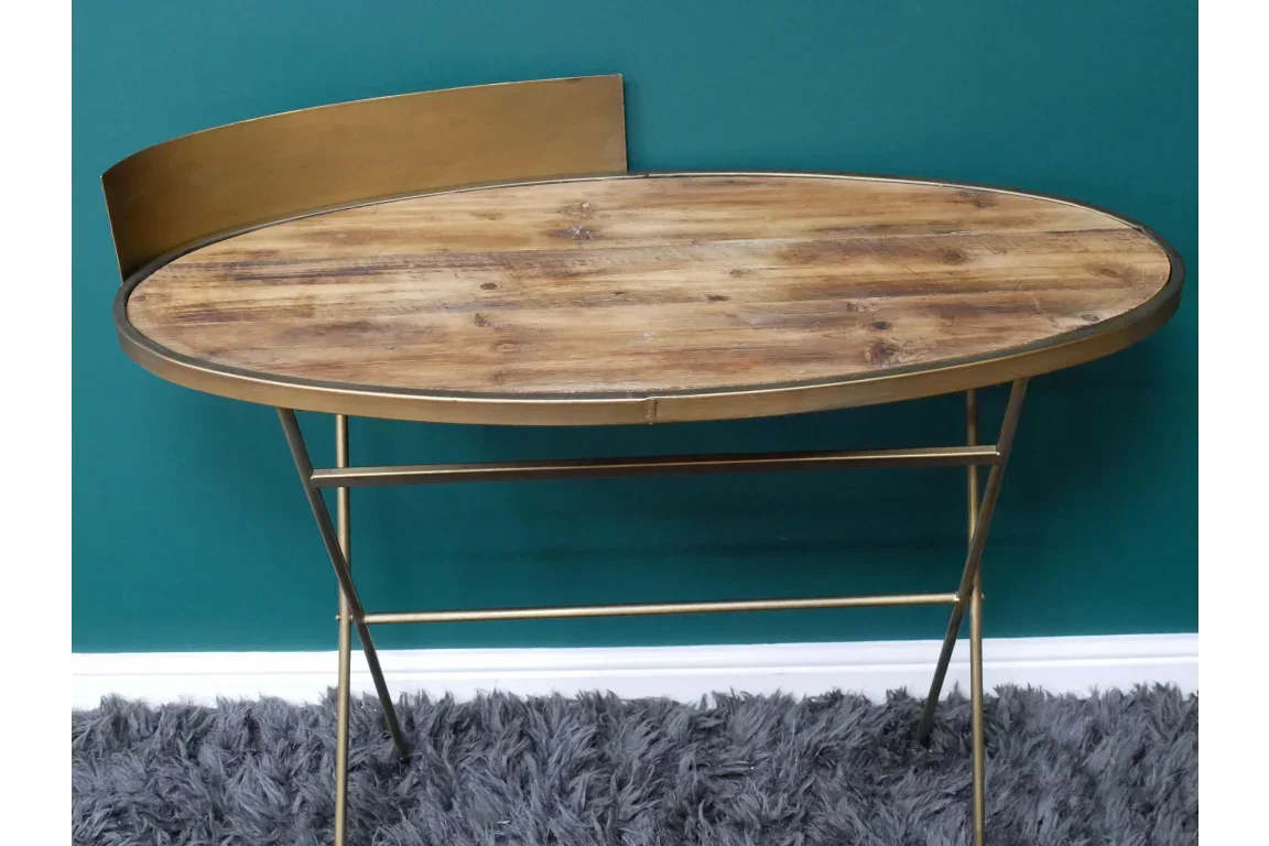 Oval wood and gold console table with metal legs against teal wall and grey rug