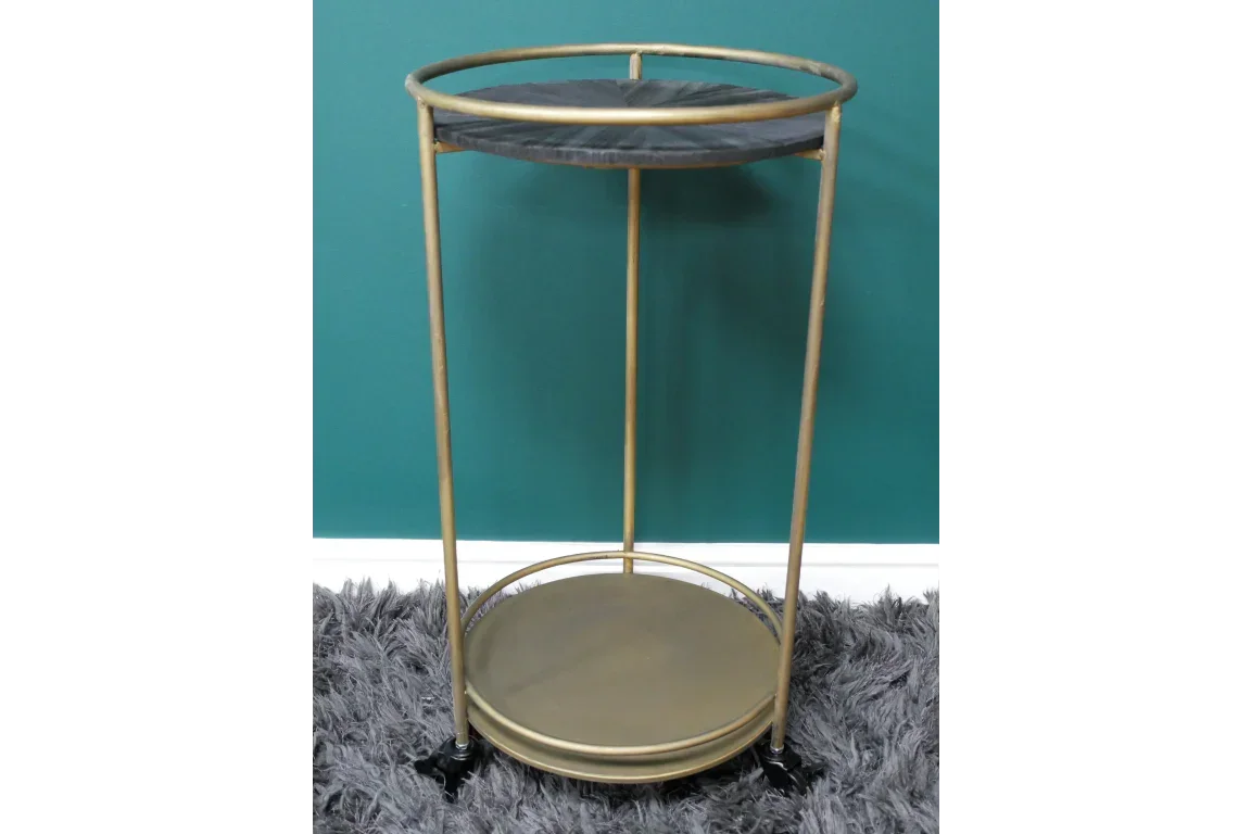 Gold metal side table with black top and bottom shelf on grey rug against green wall