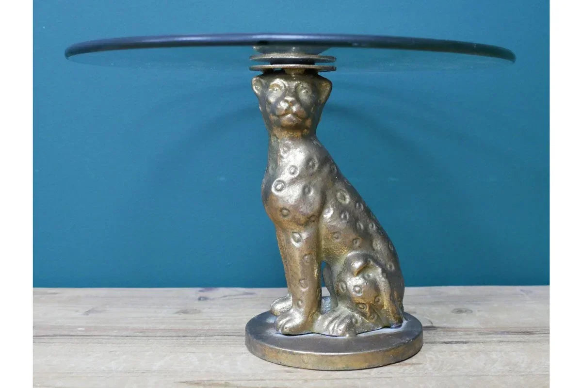 Brass cheetah side table with round glass top on wooden surface