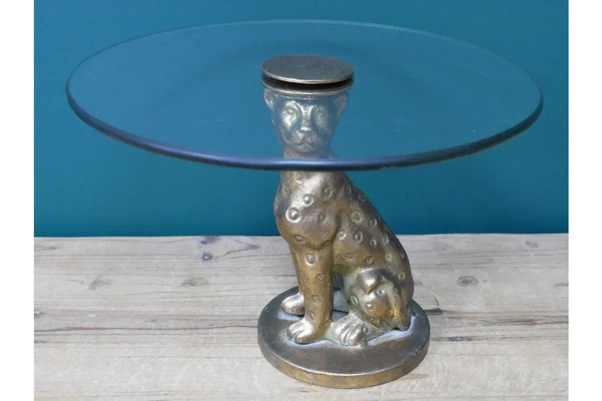 Glass side table with gold cheetah base on wooden floor against teal wall