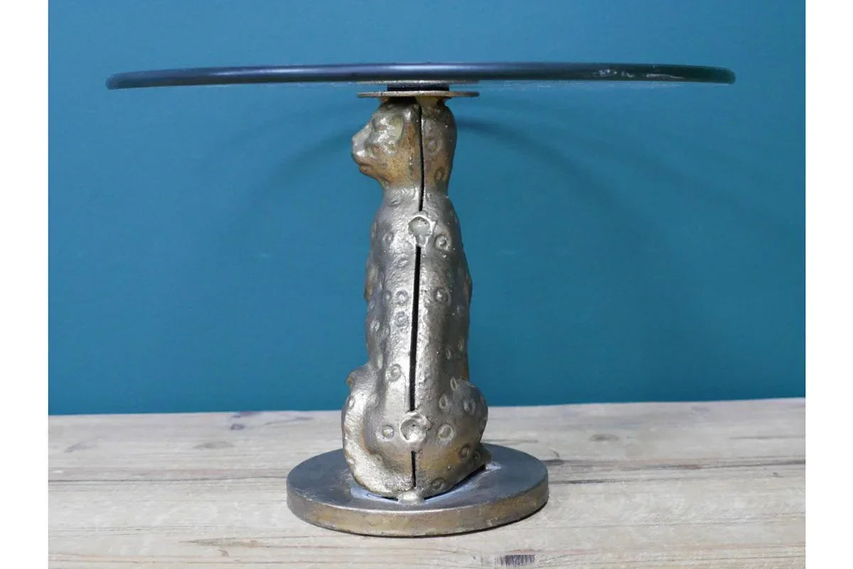 Round side table with bronze leopard base and glass top on wooden floor