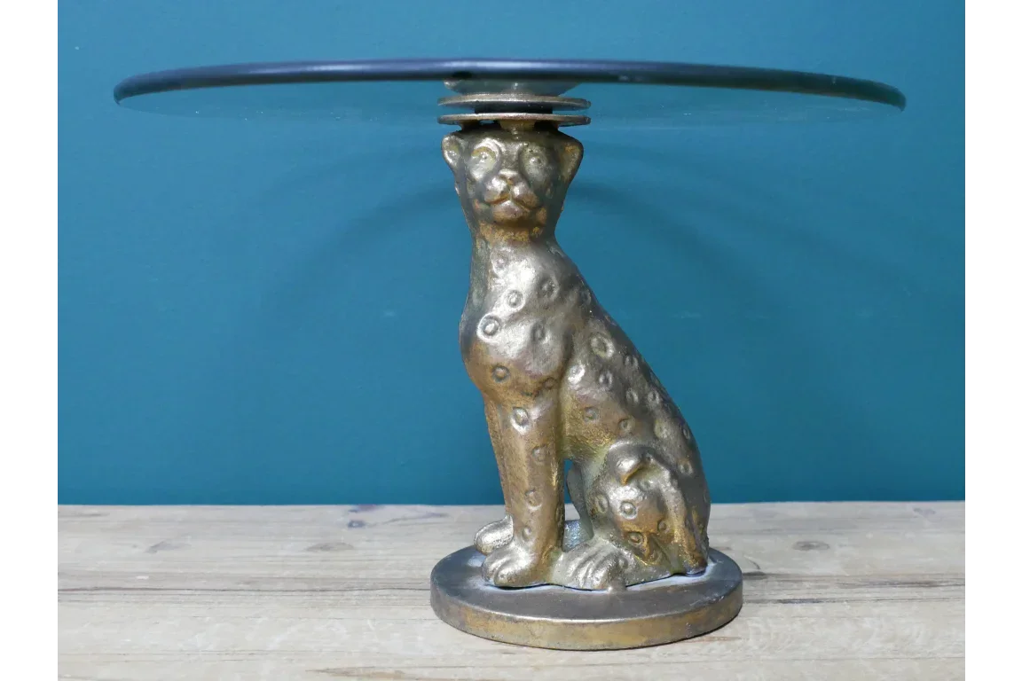 Gold cheetah base side table with round glass top on wooden surface