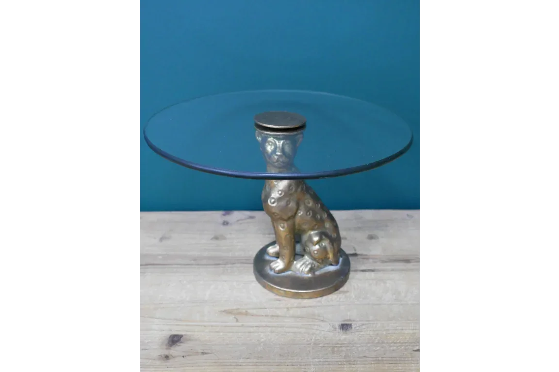 Round glass side table with gold cheetah base on wooden surface