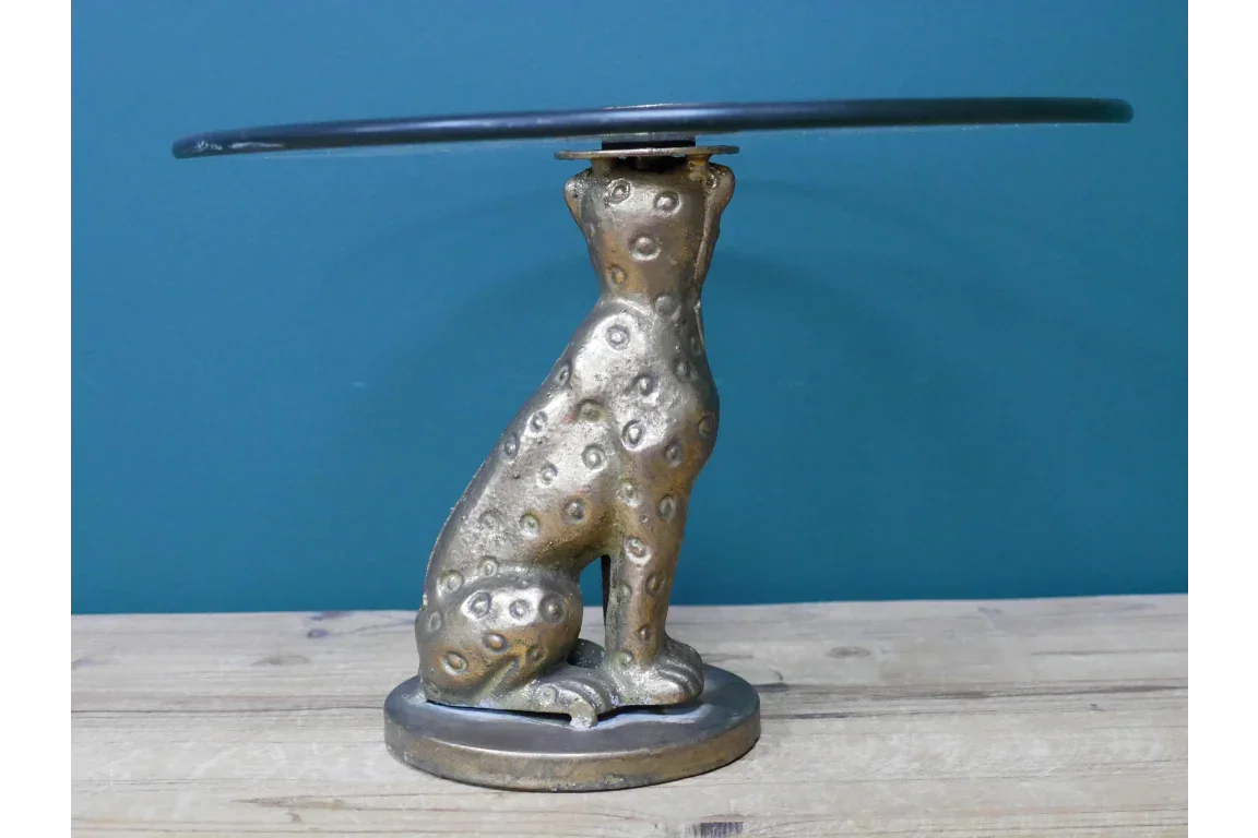 Gold animal statue side table with round glass top and textured base on wood floor