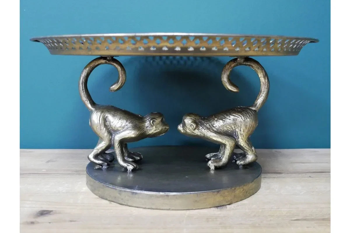 Gold metal cake stand with decorative monkey figures on round base