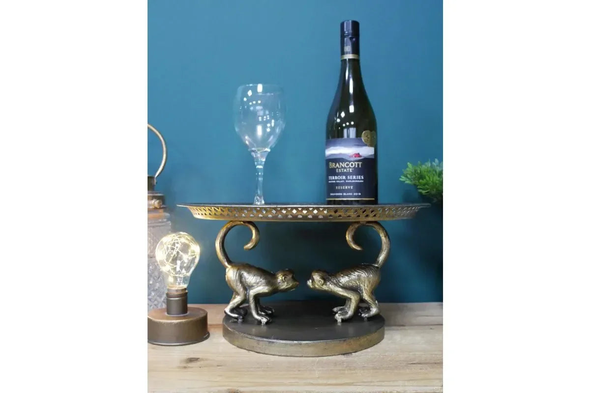Gold monkey ornament display stand with wine bottle and glass on wooden table