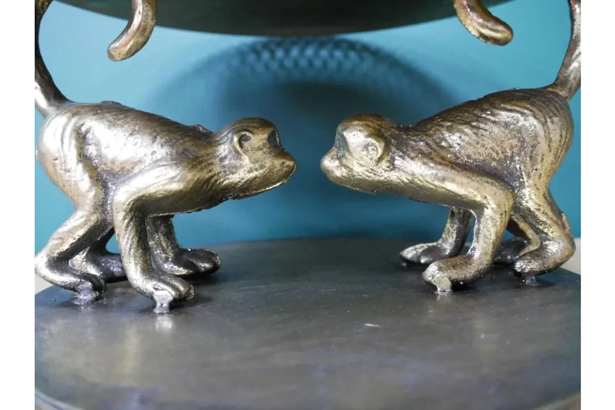 Brass monkey figurines facing each other on round metal table