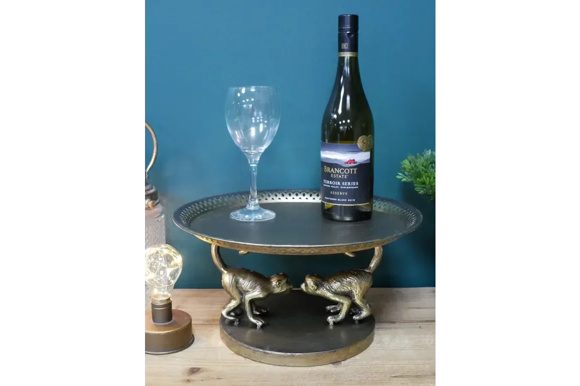 Round metal drinks tray with gold monkey figures holding base, wine bottle and glass on top