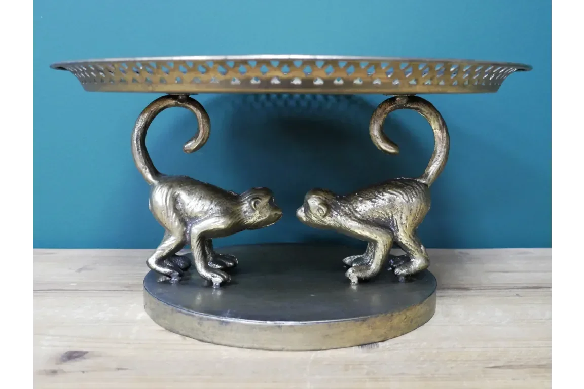 Gold metal cake stand with two monkey figurine supports and perforated edge detail