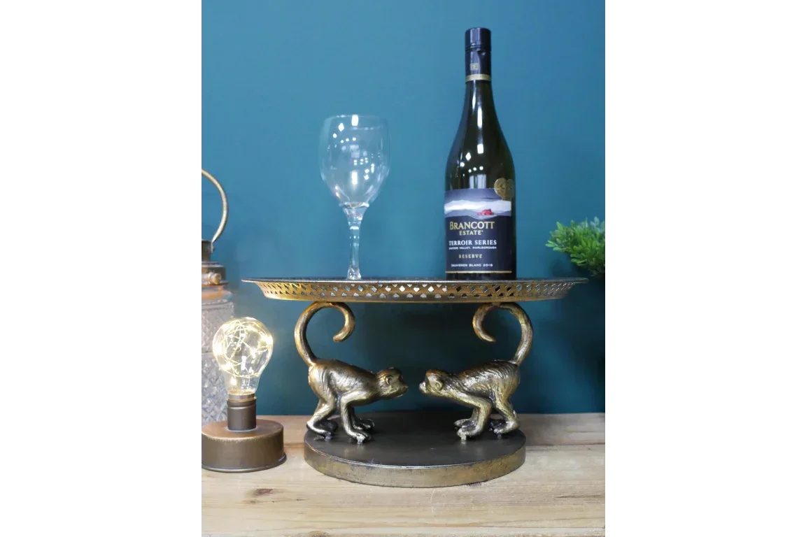 Gold monkey table with wine bottle and glass, decorative accent on wooden surface
