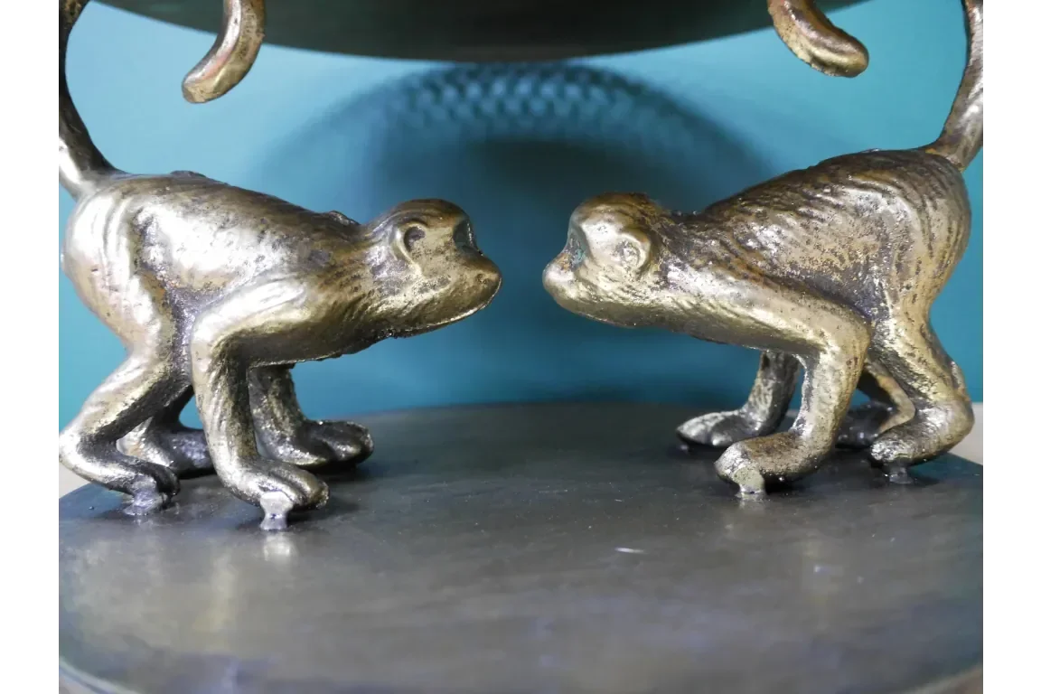 Antique brass monkey ornaments facing each other on decorative table sculpture