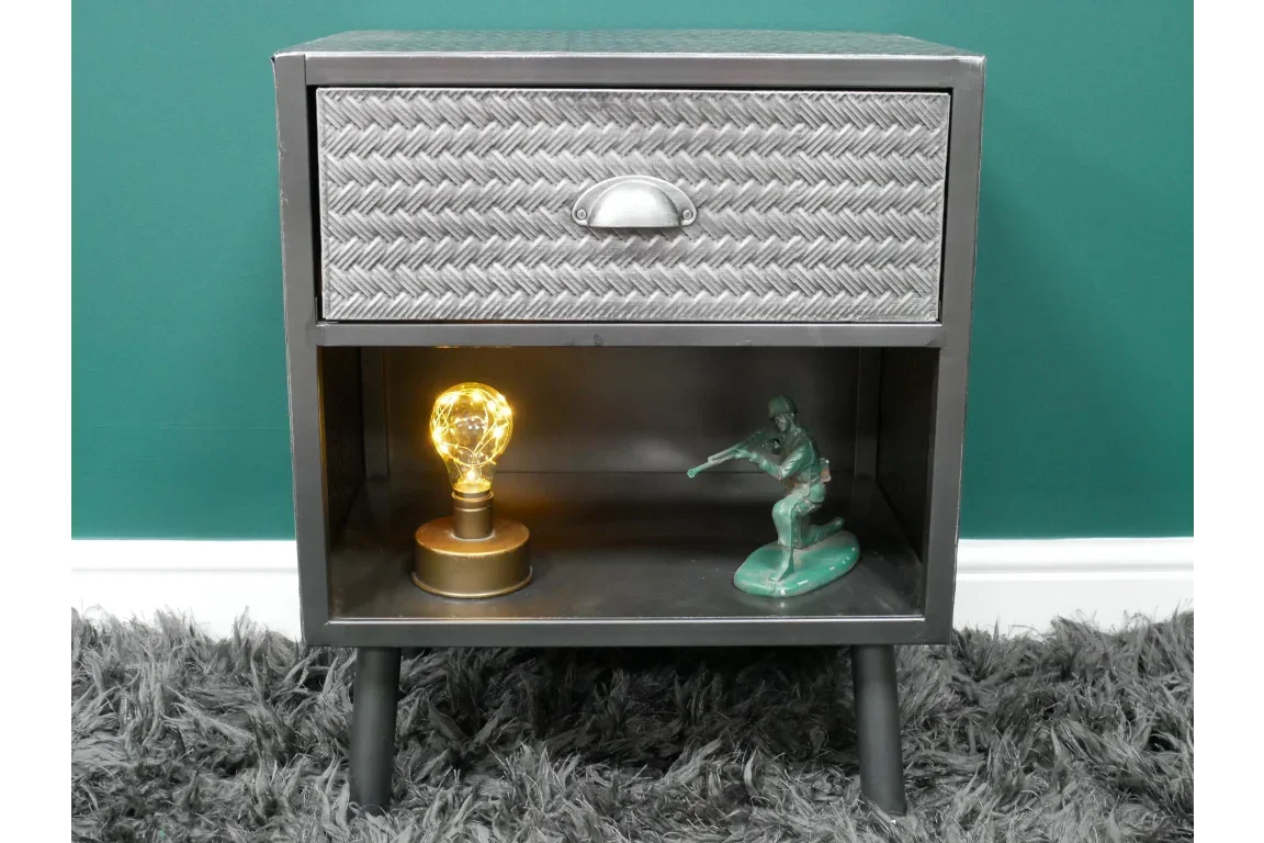 Metal bedside table with textured drawer, open shelf, lamp and figurine on grey rug