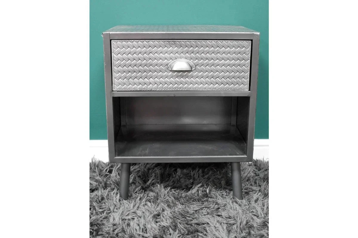 Metal bedside table with woven pattern drawer front and open shelf, placed on grey rug