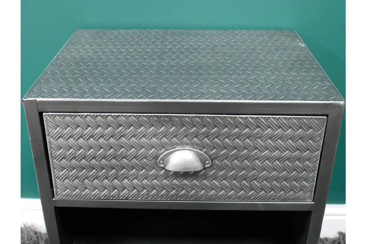 Metal bedside table with textured drawer front and cup handle against teal wall