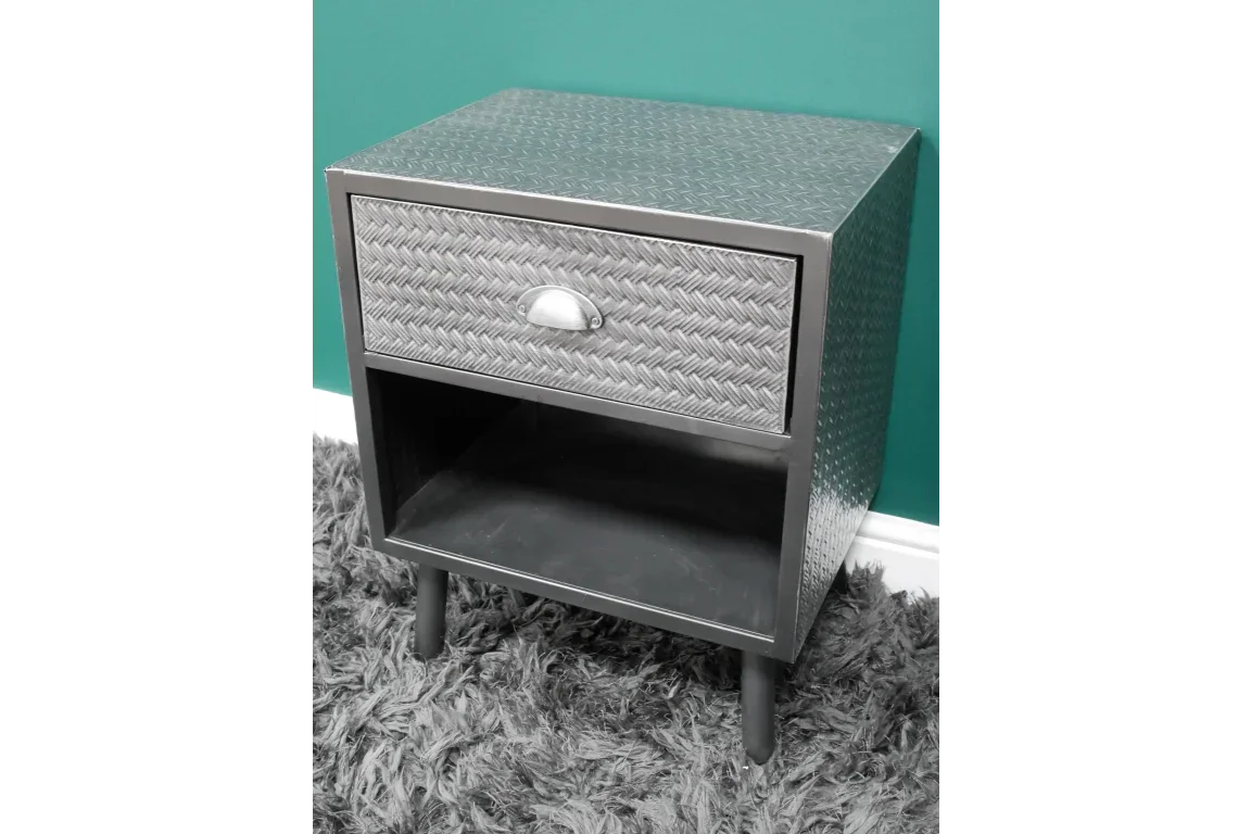 Metal bedside table with drawer, open shelf, and patterned finish on grey carpet