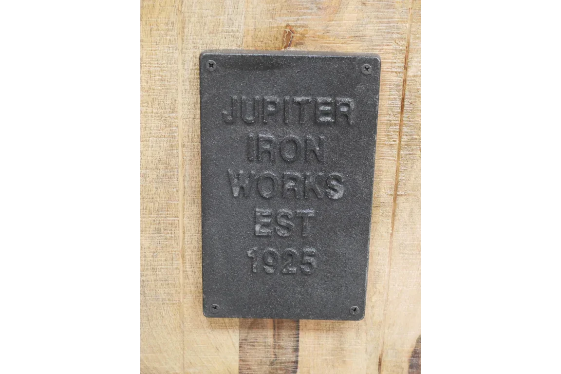 Black cast iron plaque with raised lettering on light wood furniture panel