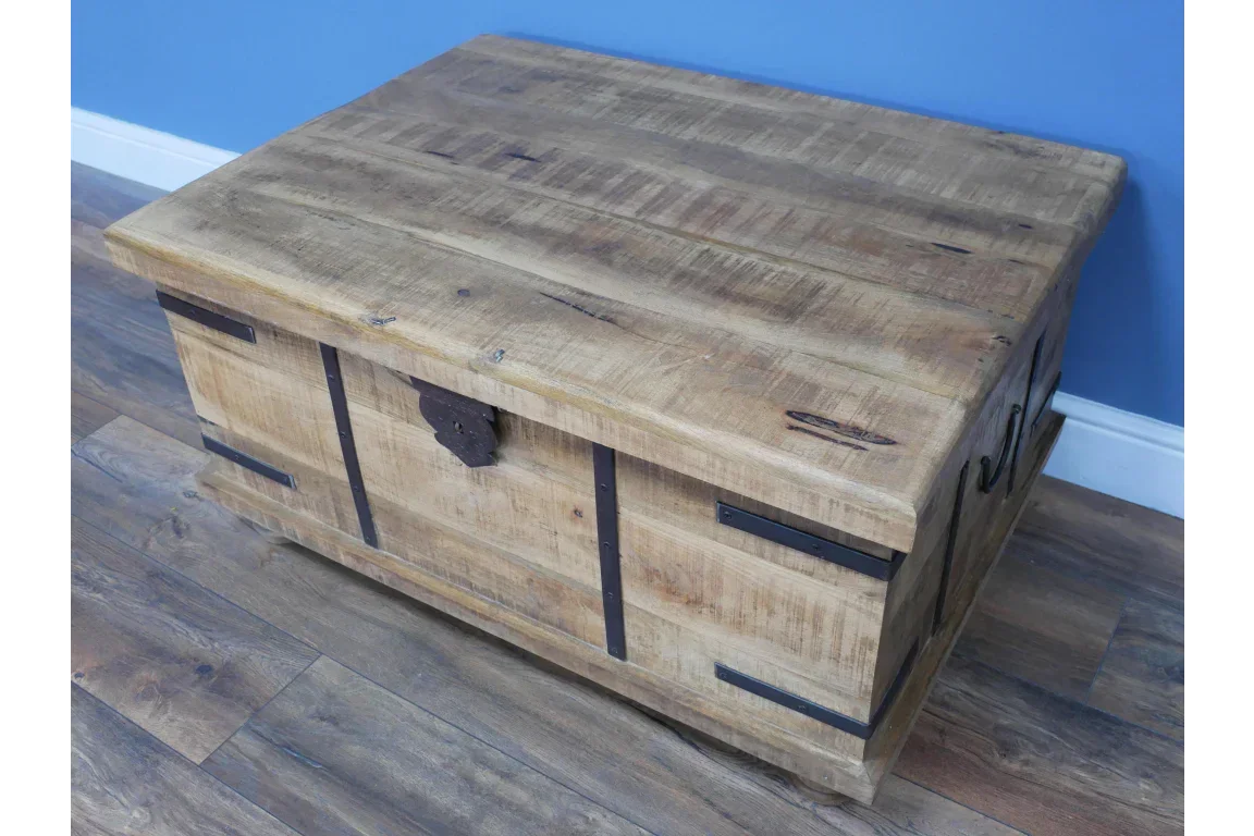 Rustic wooden storage chest with metal handles and black metal accents on wood floor