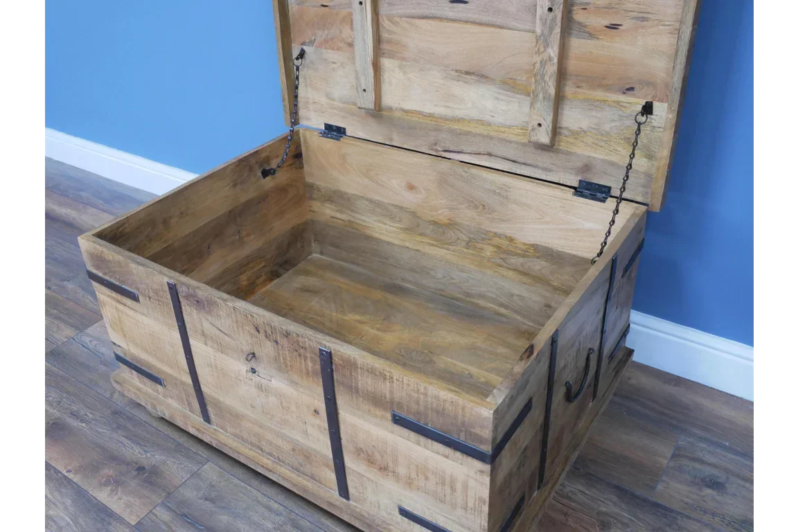 Solid wood storage chest with black metal accents and open lid on wooden floor