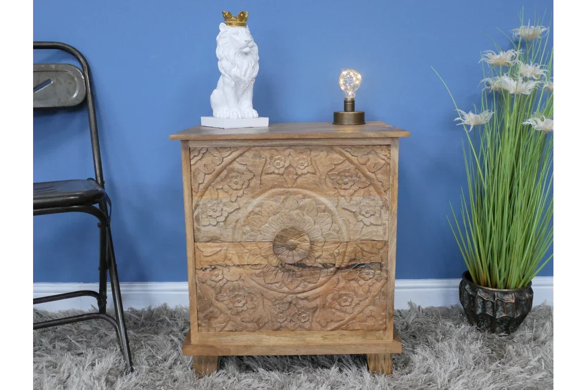 Mango wood bedside table with carved floral pattern, styled with decor and lamp