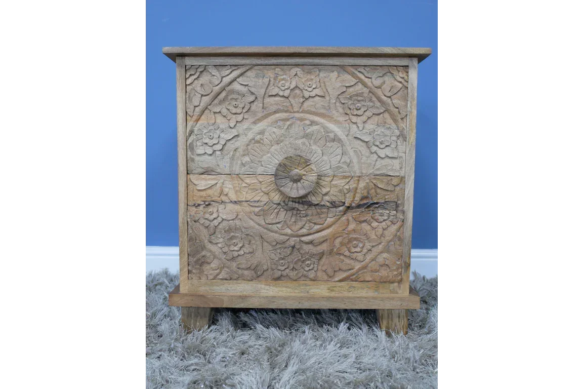 Carved wooden bedside table with floral pattern against blue wall on grey rug