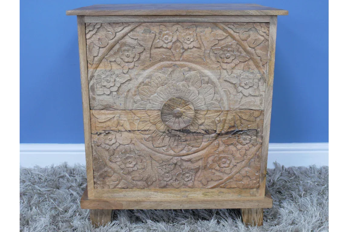Solid wood bedside table with carved floral drawer front on grey rug