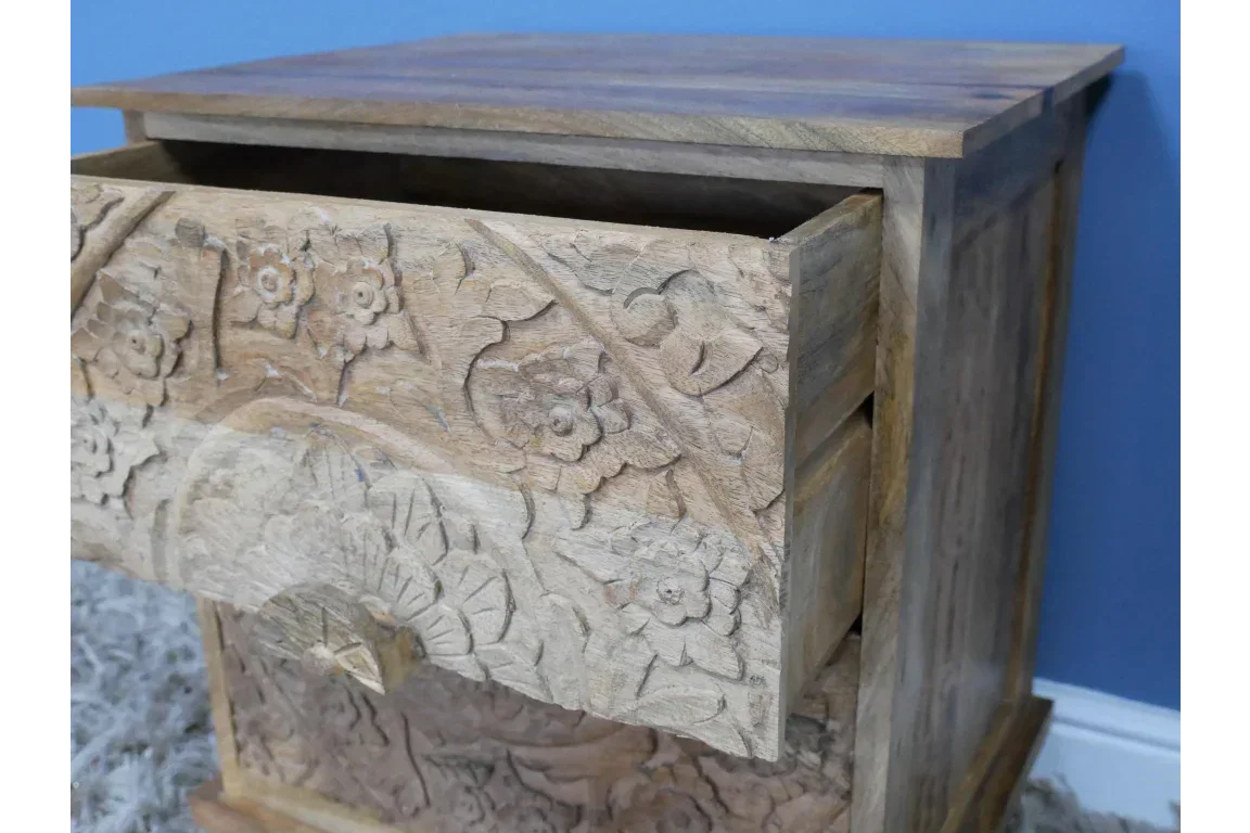 Carved wooden bedside table with open drawer and floral pattern detail