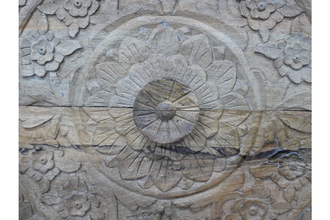 Hand-carved wooden furniture panel with floral and mandala detail in light natural wood