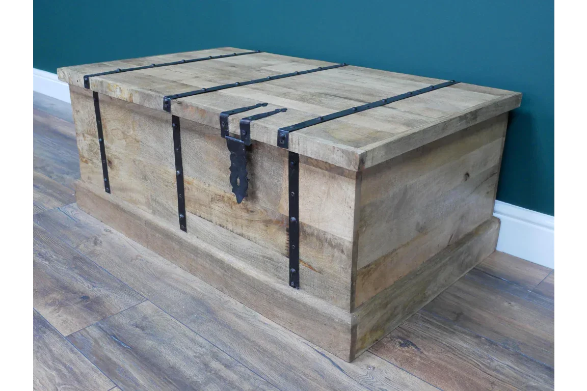 Wooden storage trunk with black metal strap detailing on a laminate floor