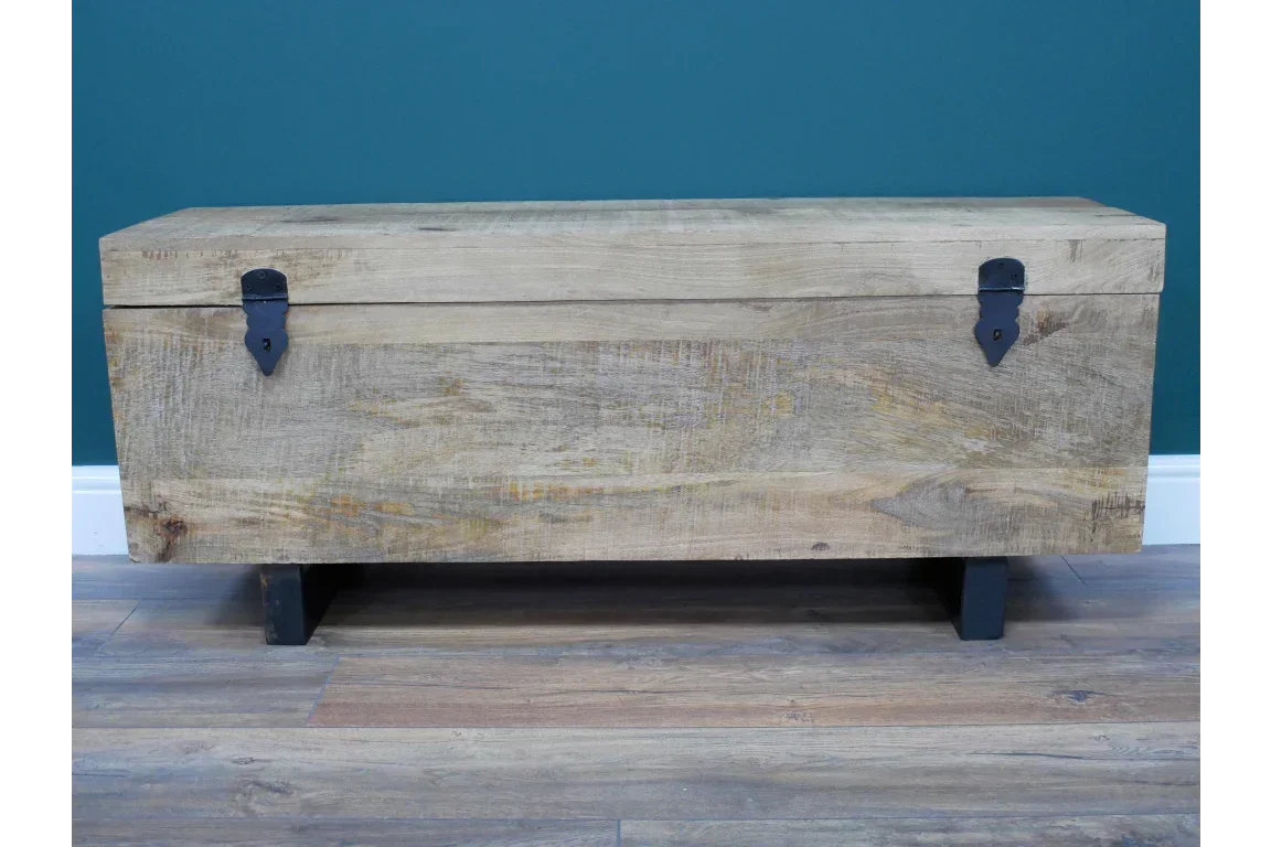 Rustic wooden storage chest with black metal hinges and legs on wooden floor