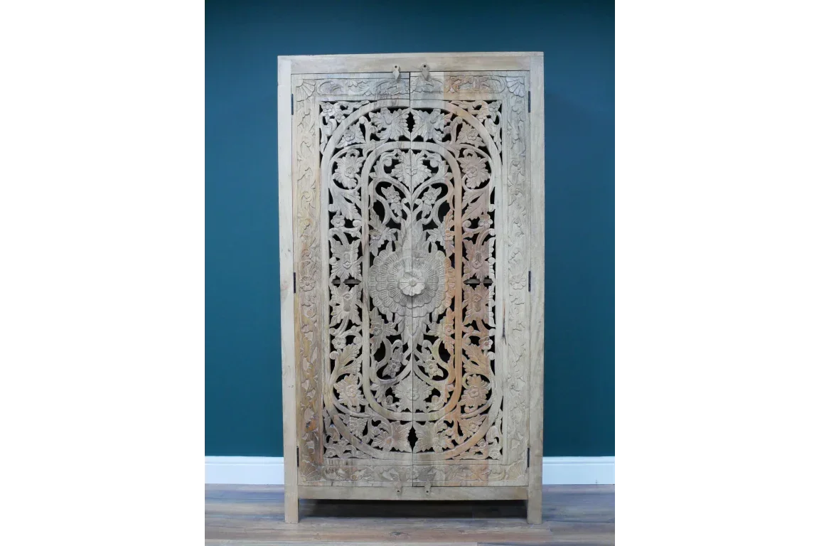 Carved wooden wardrobe with floral patterns against teal wall