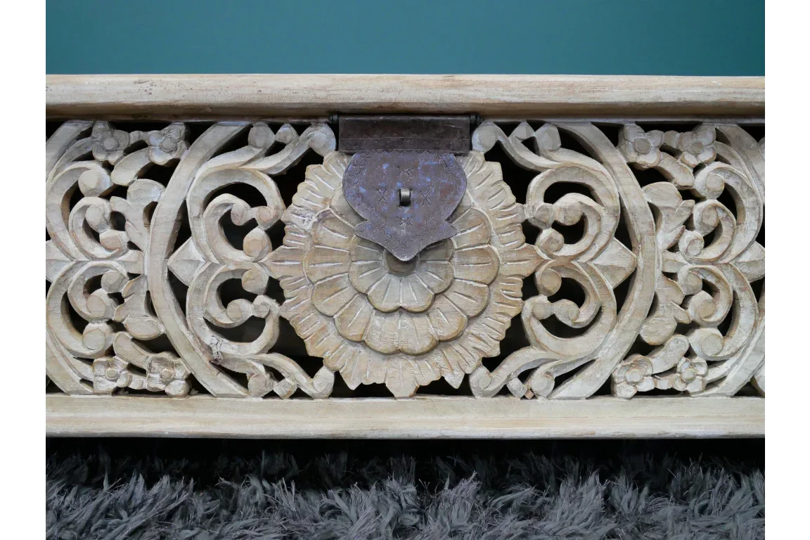 Carved wood panel with floral detail and metal latch on textured grey rug