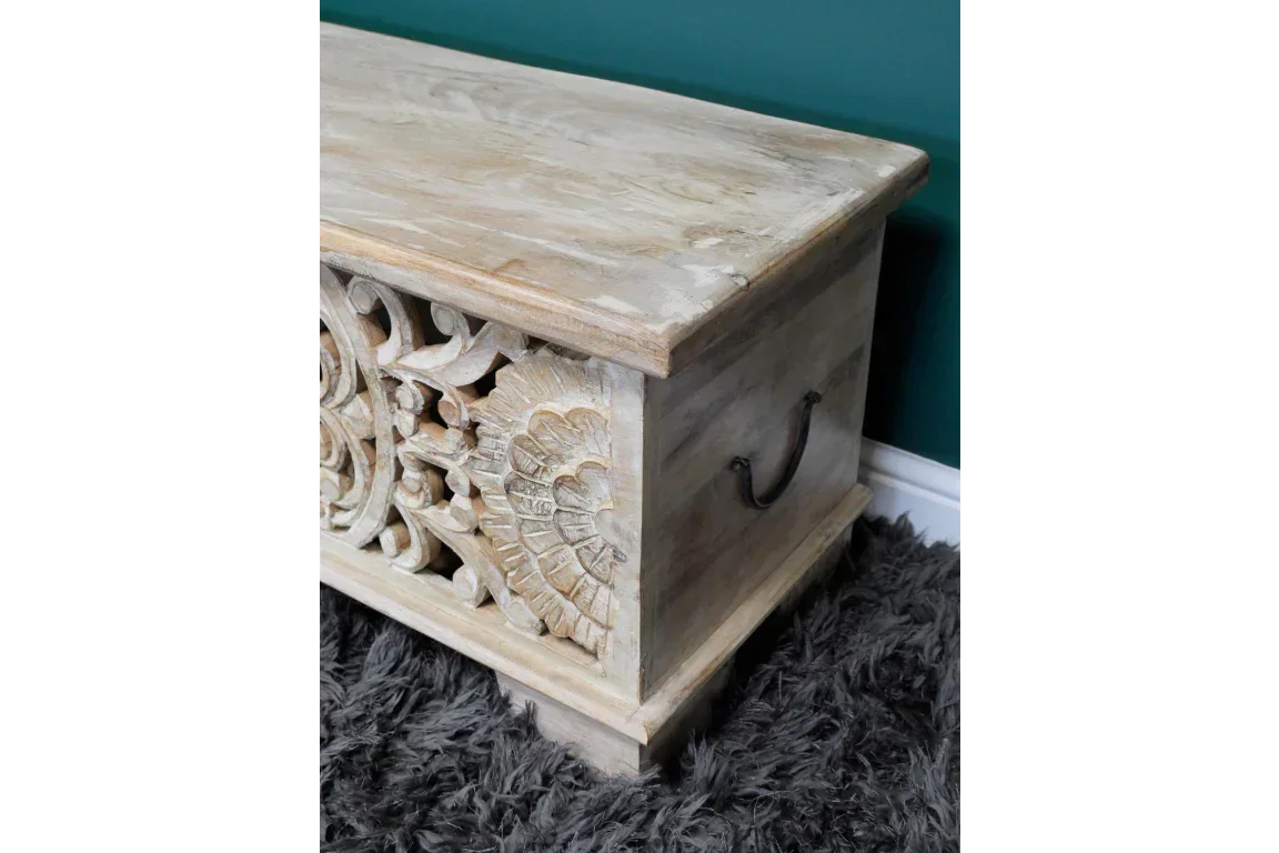 Carved wooden storage chest with ornate floral detailing and metal handles on side