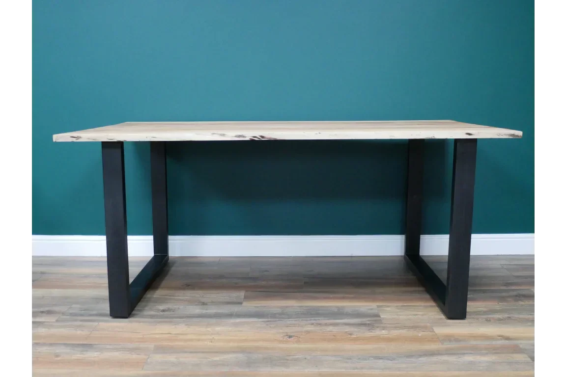 Wood dining table with black metal legs on wood flooring against teal wall