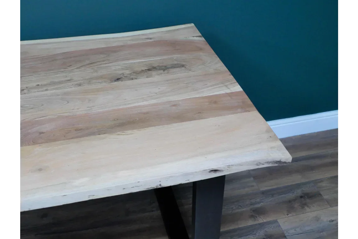 Solid wood dining table with natural grain and black metal legs, close corner view