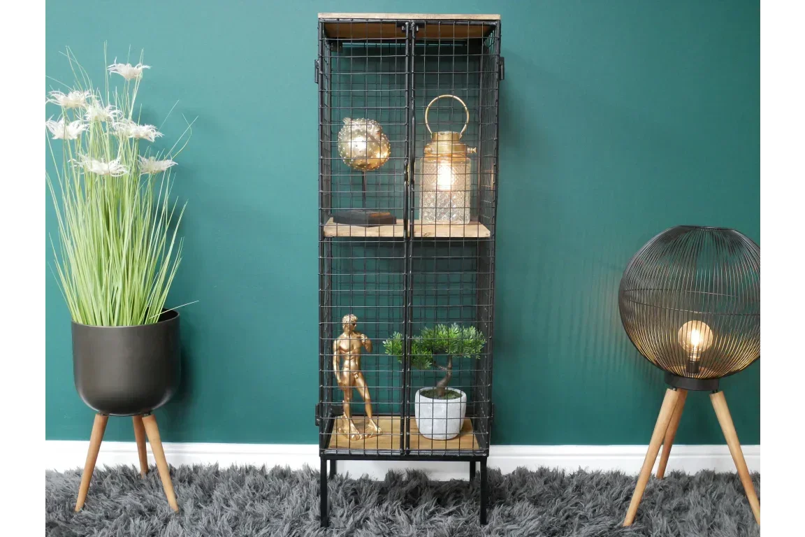 Metal wire display cabinet with wooden shelves styled with lamp, plant, and modern decor