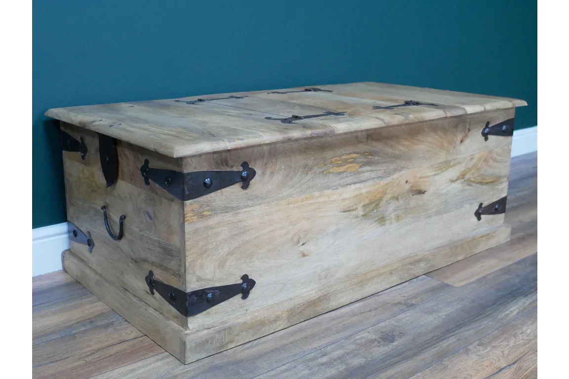 Rustic wooden storage chest with black metal hardware on wooden floor