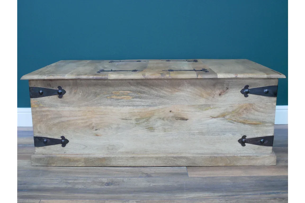 Solid wood storage chest with black metal hinges and rustic finish on wooden floor