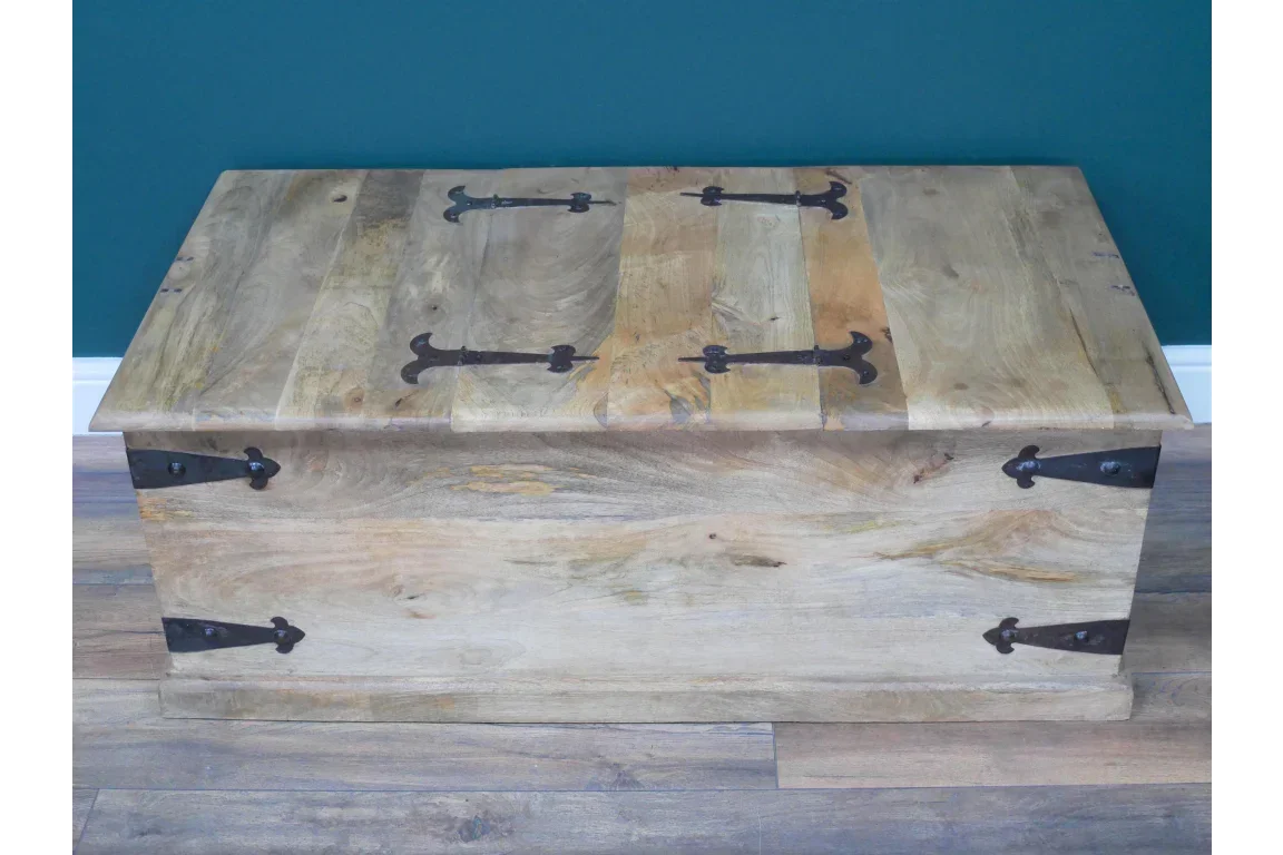 Solid wood storage chest with metal hinges and rustic finish placed on wooden flooring