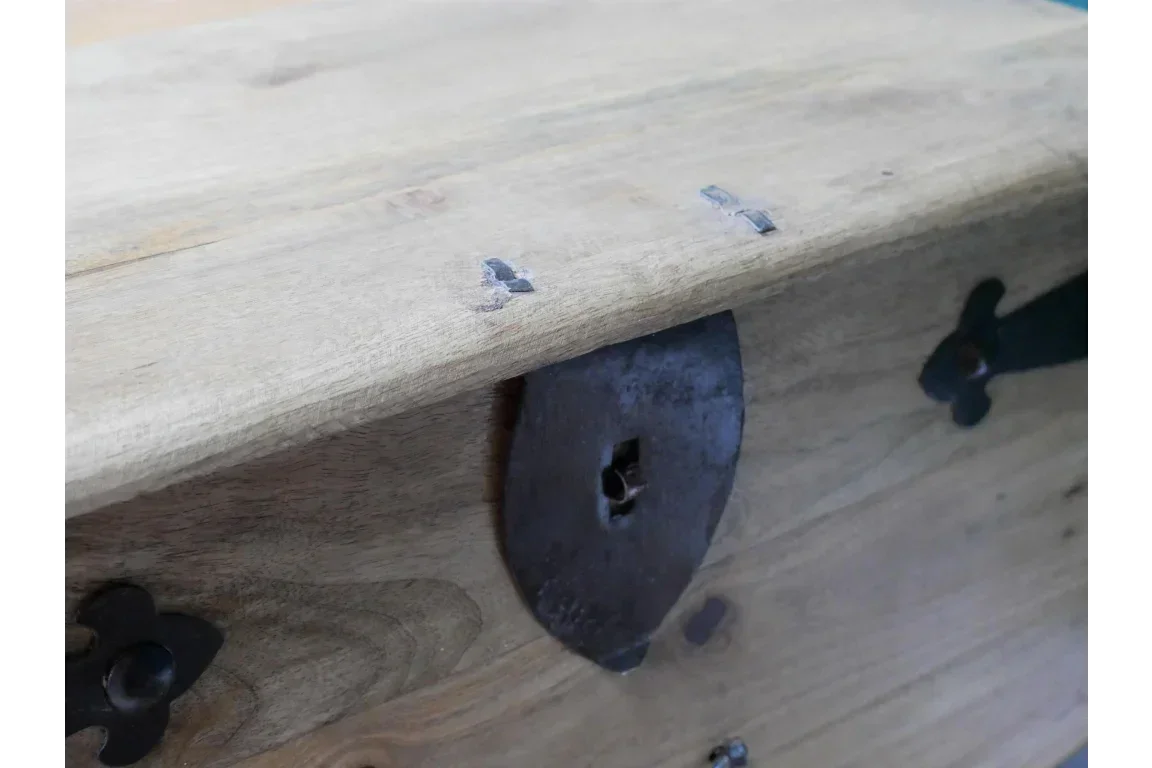 Natural wood chest corner with dark metal lock and visible wood grain texture
