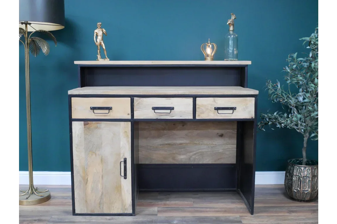Industrial wood and metal desk with three drawers and cupboard against teal wall