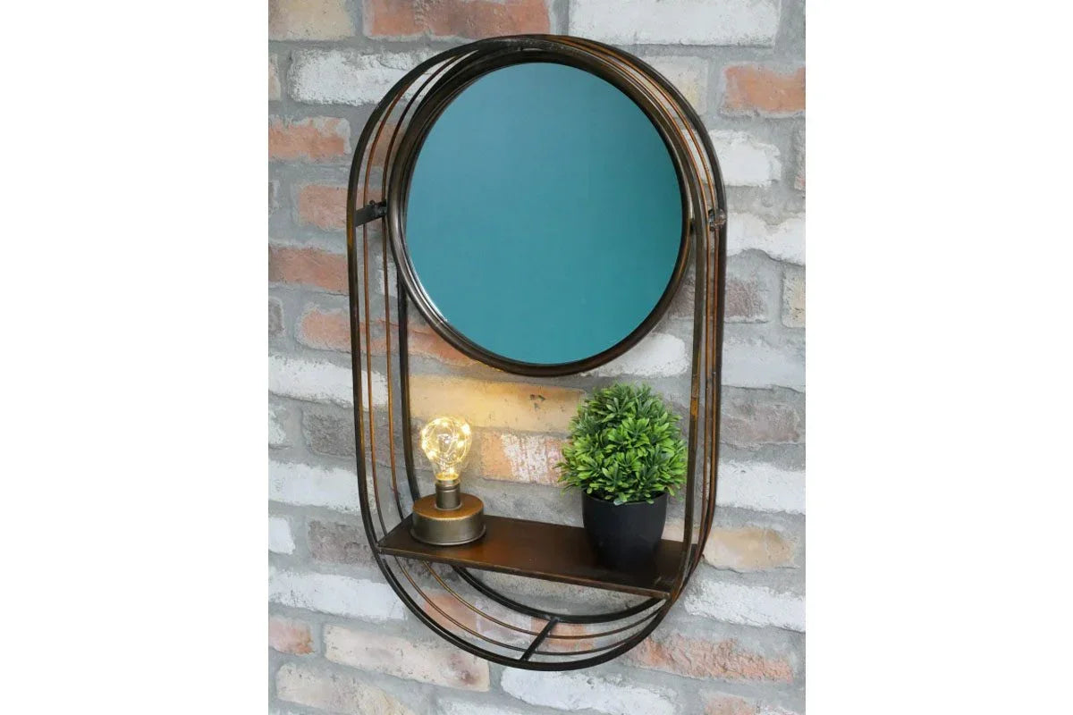 Round wall mirror with black metal frame, built-in shelf, small lamp, and potted plant