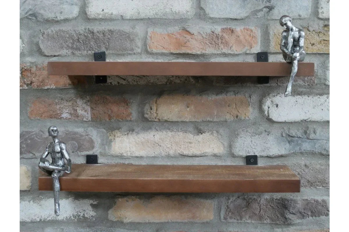 Wall mounted wooden shelves with metal figure ornaments against rustic brick backdrop
