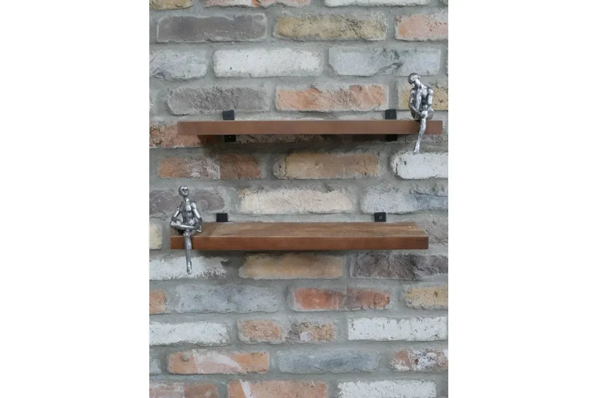 Wall mounted wooden shelves with silver figurines on brick background
